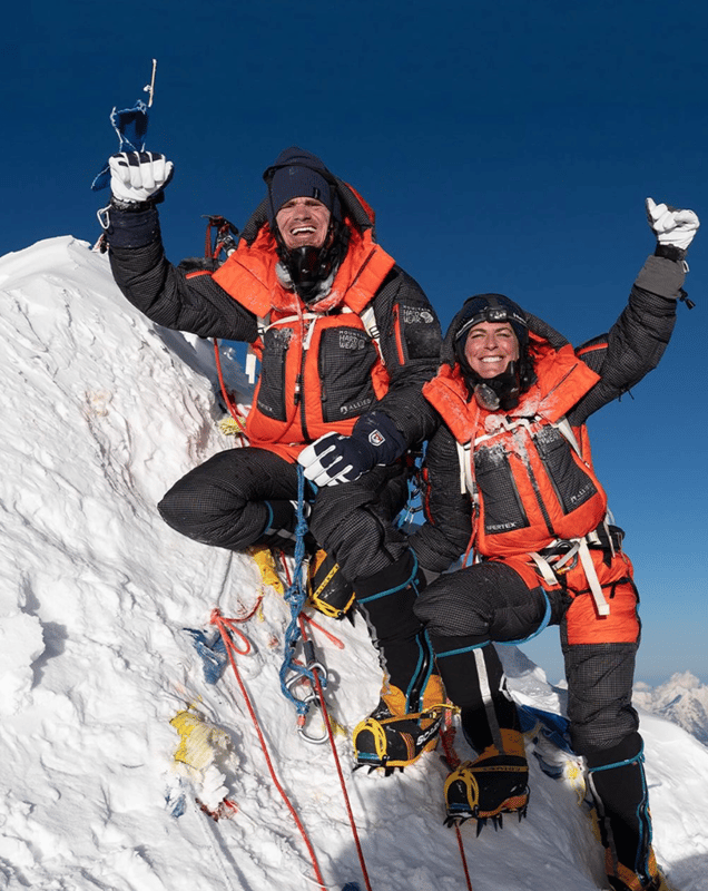 Scott Lehmann and Shayna Unger have their fists raised in victory standing atop Manaslu. 