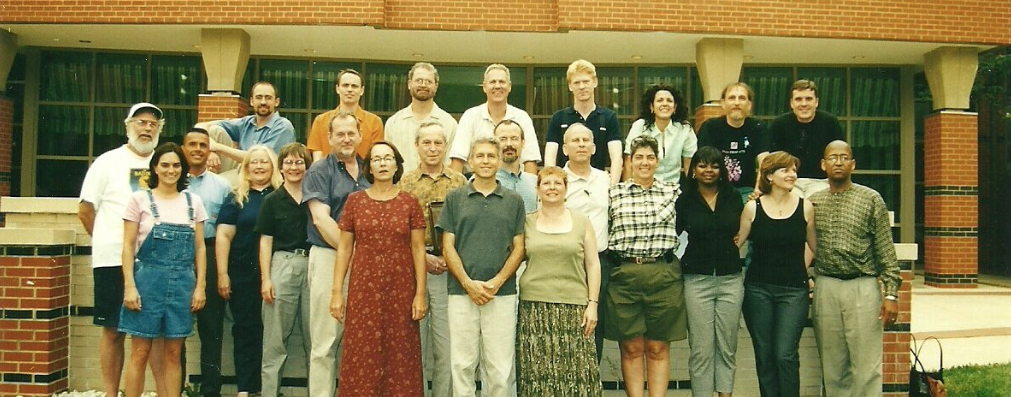 A group of people pose outdoors in two rows. 