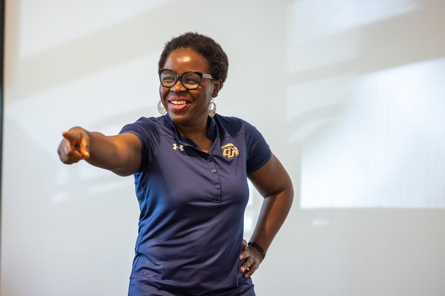 Provost Rashid, wearing a blue Gallaudet polo, smiling and pointing to something off camera. 